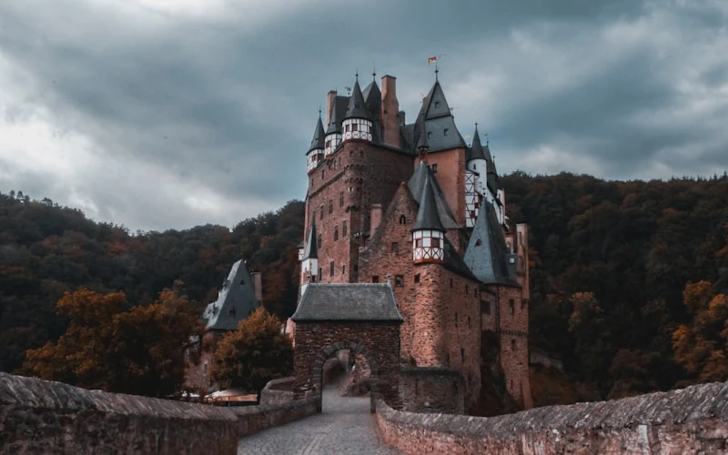 A castle among autumn trees under a stormy sky
