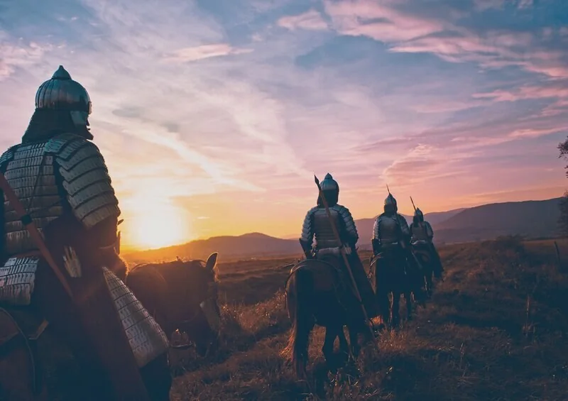 Armored riders crossing a field at sunset